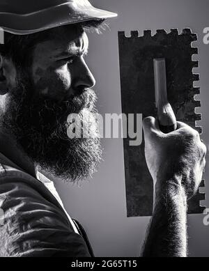 Bearded man worker, beard, building helmet, hard hat. Plastering tools. Builders in hard hat, helmet Stock Photo