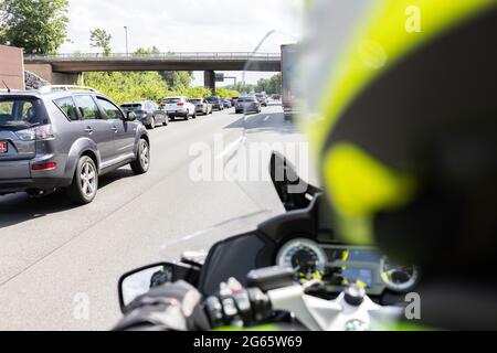 02 July 2021, North Rhine-Westphalia, Königsforst: Dust consultant Herbert Kleefuß from the ADAC rides his motorcycle between cars on the Autobahn 4. Photo: Marcel Kusch/dpa Stock Photo