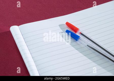 writing equipment blue and ren  ballpoint pens with green top that placed on the lined paper Clean sheet of notebook for school notes Stock Photo