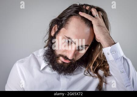 portrait of a young middle eastern businessman with beard and long hair adjusting his hair Stock Photo