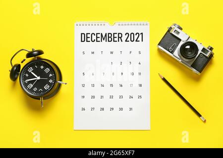 Flip paper calendar, pencil, alarm clock and photo camera on color background Stock Photo