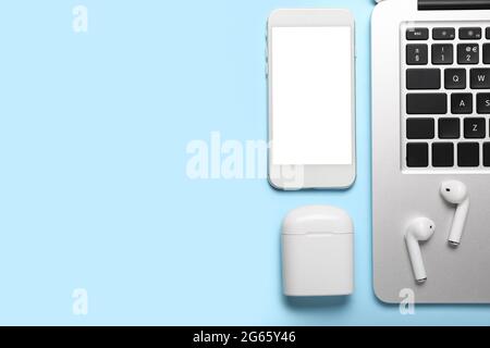 Modern earphones, laptop and mobile phone on color background Stock Photo