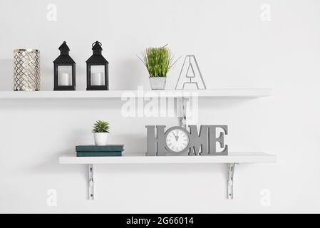 Book shelves with decor hanging on light wall Stock Photo