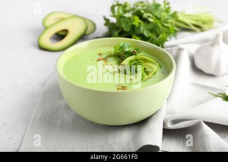 Bowl with green gazpacho, avocado and parsley on light background Stock Photo