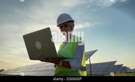 Inspector Engineer Woman Holding Digital laptop Working in Solar Panels Power Farm, Photovoltaic Cell Park, Green Energy Concept. Stock Photo