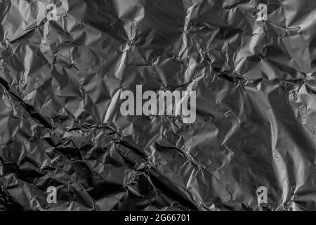 Black crushed damaged aluminum metal foil texture. Grunge wrinkles. Abstract dark background Stock Photo