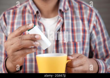 young man putting artificial sweetener in tea, Stock Photo
