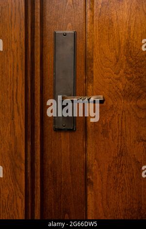 Photograph of a brass handle, with patina on a mahogany stained solid wood door Stock Photo