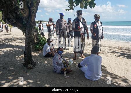 Denpasar, Indonesia. 3rd July, 2021. Members of the Balinese traditional security personnel, the pecalang, and police officers patrol at the Sanur beach tourism site as part of local COVID-19 restriction measures in Denpasar, Bali, Indonesia, July 3, 2021. Indonesia on Saturday recorded 27,913 new cases of COVID-19 in the past 24 hours, another record of the daily spike, bringing the total tally to 2,256,851, the Health Ministry said. Credit: Bisinglasi/Xinhua/Alamy Live News Stock Photo