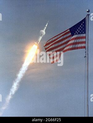 The American flag heralds the flight of Apollo 11, the first Lunar landing mission. The Apollo 11 Saturn V space vehicle lifted off with astronauts Neil A. Armstrong, Michael Collins and Edwin E. Aldrin, Jr., at 9:32 a.m. EDT July 16, 1969, from Kennedy Space Center's Launch Complex 39A. During the planned eight-day mission, Armstrong and Aldrin will descend in a lunar module to the Moon's surface while Collins orbits overhead in the Command Module. The two astronauts are to spend 22 hours on the Moon, including two and one-half hours outside the lunar module. Stock Photo