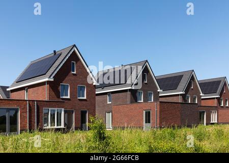 Solar panels on the roof of new built houses in The Netherlands collecting green energy from the sun in a modern and sustainable way. New technology o Stock Photo