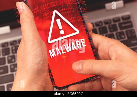 Malware concept with person using smartphone, background of the laptop Stock Photo