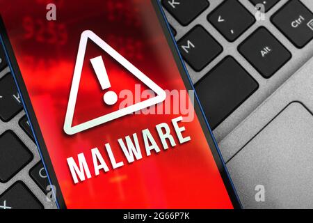 Mobile phone with malware sign on the screen, background of laptop, spyware and security system concept photo Stock Photo