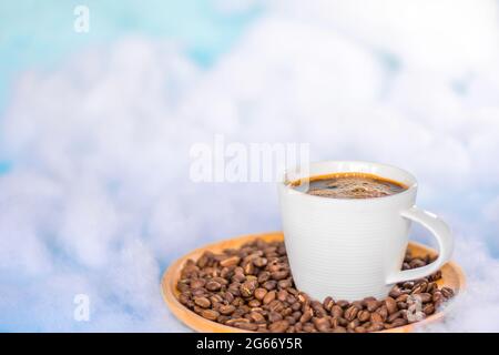 Coffee and beans on a round wooden tray, floating in the sky with white clouds. Copy space. Stock Photo