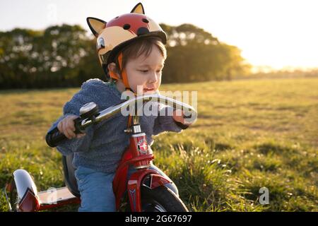 A young boy riding a tricycle Stock Photo