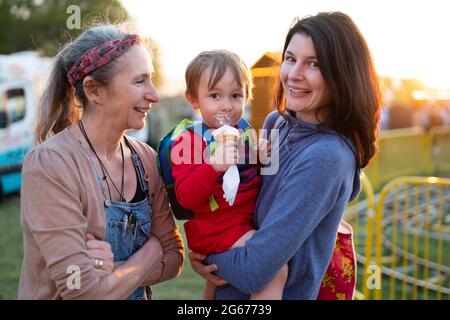 A mother and grandmother holding a child eating an ice cream cone Stock Photo