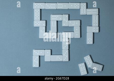 Light Blue wood domino pieces on light blue background. Leisure games concept. Stock Photo