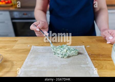 The process of making homemade pies with cottage cheese and dill. The cook puts stuffing in to the dough. Stock Photo
