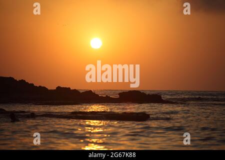 Sunset, waves and reflections over the Mediterranean Sea water and Sandstone rocks of the Dor Habonim Beach Nature Reserve. Israel. Stock Photo