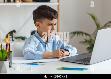 Cute little boy home schooling studying with his gadget laptop