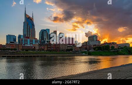 Nashville, Tennessee - 27 June 2021: Sunset behind the financial downtown district of Nashville reflected into Cumberland River Stock Photo