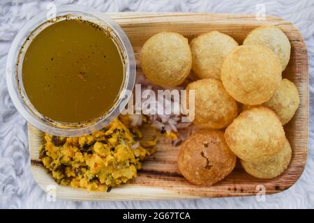 Tasty Indian snacks Pani puri with chat masala water and sliced onions. Traditional indian snack dish also known as Water balls, Golgappe, puchka. Stock Photo