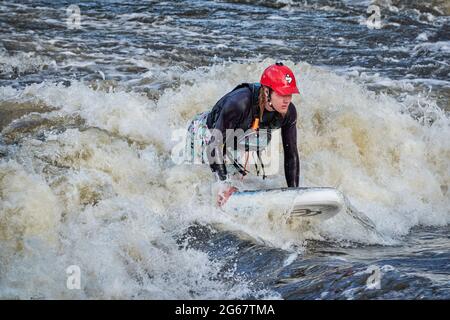 Fort Collins, CO, USA - May 7, 2021: Young male is surfing a wave in the Poudre River Whitewater Park.