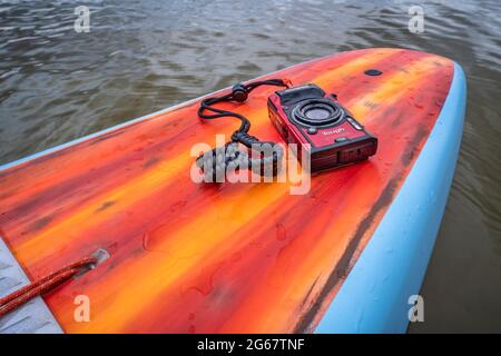 Fort Collins, CO, USA - May 9, 2021: Compact, waterproof Olympus Stylus Tough TG-5 camera on a rear deck of a stand up paddleboard by Mistral.