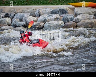 Fort Collins, CO, USA - May 7, 2021: Young male kayaker surfing a wave in the Poudre River Whitewater Park.