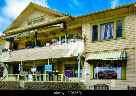 Old  wooden two storied multi-use building now mixing potted plant balcony dweller with Neon sign for Psychic palm & tarot readings in San Diego, CA Stock Photo