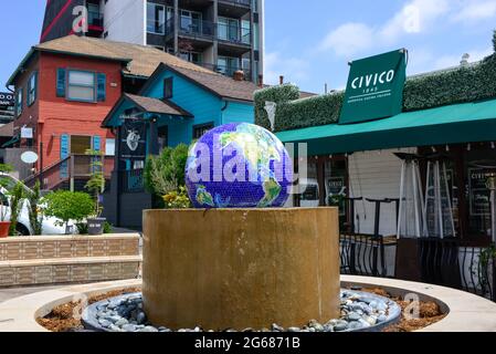 The landmark blue mosaic globe water fountain at Piazza Basilone in Little Italy, with shops, restaurants and condos nearby  in San Diego, CA, USA Stock Photo
