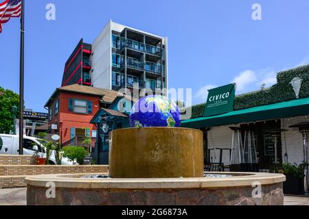 The landmark blue mosaic globe water fountain at Piazza Basilone in Little Italy, with shops, restaurants and condos nearby  in San Diego, CA, USA Stock Photo