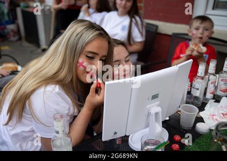 Young residents are putting on make-up and face-paint to support the England team.A football fan, Chris Ralph Dowes, organized the decoration of over 400 St George's flags displayed in the Kirby Estate in South-East London together with other residents ahead of the start of the tournament of UEFA Euro 2020. The tradition of the estate to put up hundreds of St George's flags was since the Euro 2012 and each times the residents managed to fit more flags into the estate. During each game by the England team, Chris will be the host and invite other residents to join watching. He said all the flags Stock Photo