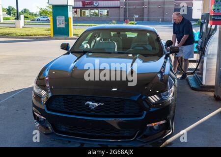 A man pumps gasoline into a black 2015 Ford Mustang at a Murphy USA gas station in Fort Wayne, Indiana, USA. Stock Photo