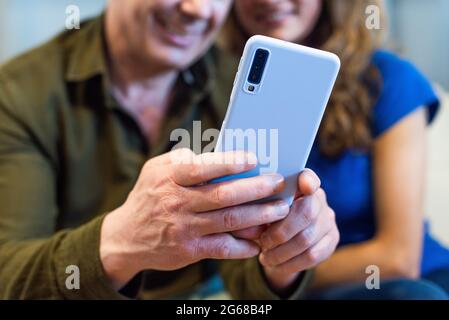 Detail of unrecognizable couple looking at the mobile smiling. Stock Photo