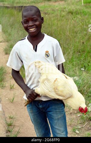 UGANDA. PORTRAIT OF A YOUNG MAN SELLING CHICKEN ON THE ROAD. Stock Photo