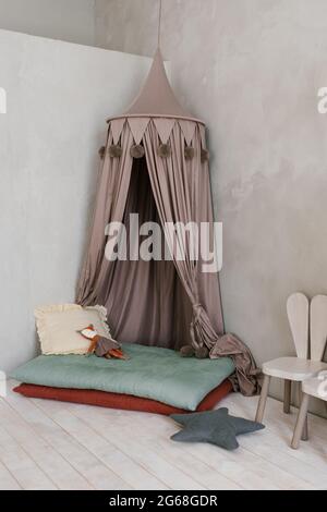 Modern children's room: a tent bed on the podium, soft toys, high chairs in the form of bunnies in light colors Stock Photo