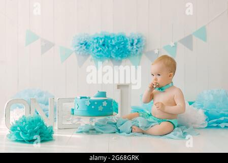 Birthday party for a one-year-old boy in blue and turquoise garlands and a cake, holiday concept and decor, a child with a cake Stock Photo