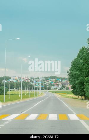 road near the village. gray clouds across the sky. empty road. zebra crossing Stock Photo