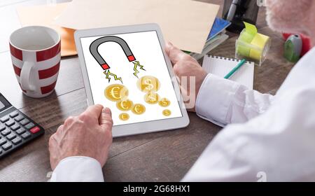 Money attraction concept shown on a tablet held by a man Stock Photo