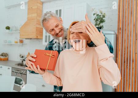 husband gives a gift to her wife at home Stock Photo
