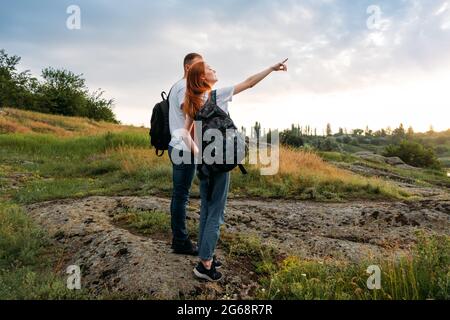 Adventure, Hiking, Trekking, Bushcraft Concept. Solo family travel. Local travel. Young happy couple travelers hiking with backpacks on rocky trail on Stock Photo