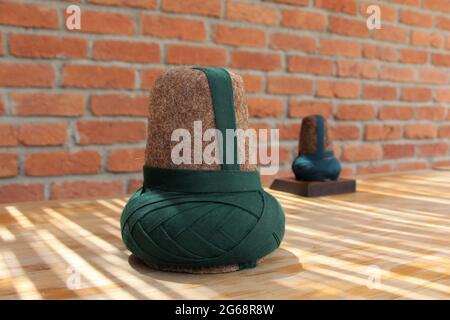 A hat made of felt worn by the whirling dervishes. The brown hat worn by the Mevlevi dervishes. There is a brick wall in the background. Stock Photo