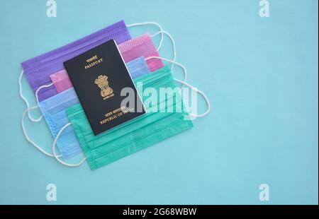 Mandi, Himachal Pradesh, India - 04 24 2021: Concept of travel during Coronavirus pandemic (Covid19 crisis), High angle view of Indian passport over multi color medical face mask (Protective mask) Stock Photo