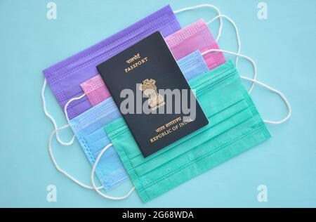 Mandi, Himachal Pradesh, India - 04 24 2021: Concept of travel during Coronavirus pandemic (Covid19 crisis), High angle view of Indian passport over multi color medical face mask (Protective mask) Stock Photo