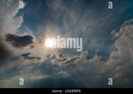 Shining sun with rays in the clouds in the blue sky Stock Photo