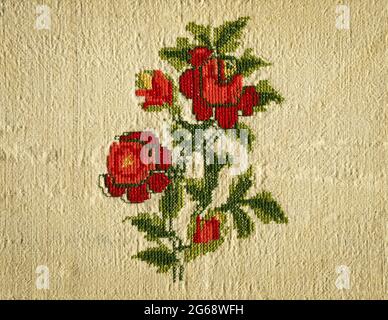Cross-stitch needlework stitching on beige linen cloth and embroidered red rose, handmade cross stitch Stock Photo