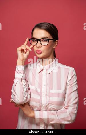 Clever successful young woman wearing glasses on red background Stock Photo