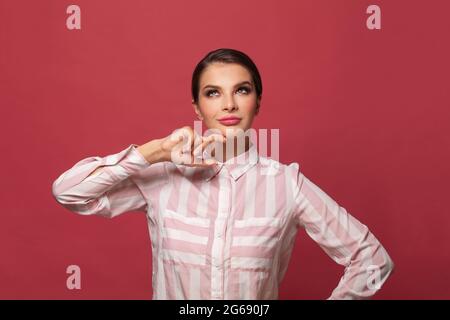 Young woman wearing casual shirt standing over red background looking up with smile on face and thinking, natural expression Stock Photo