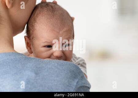 Baby Behavior. Closeup Portrait Of Young Mother Comforting Her Crying Infant Child Stock Photo